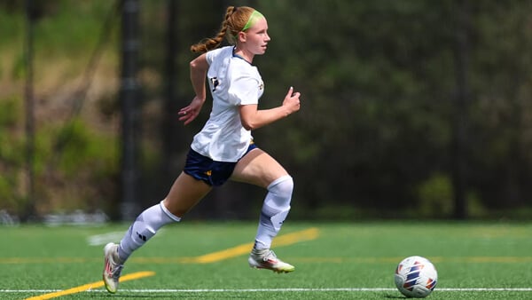 A Quinnipiac women's soccer player dribbles the ball across the field