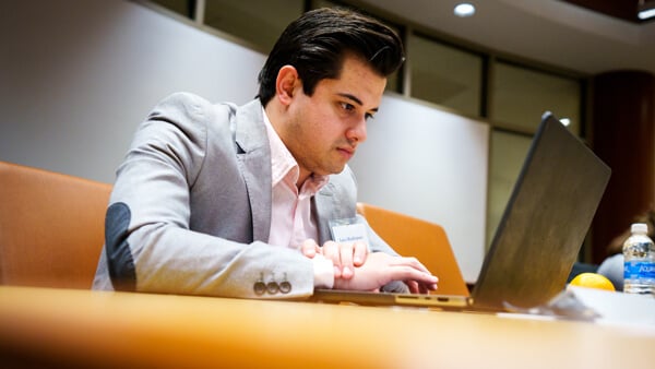 A student in professional-attire works on a laptop.