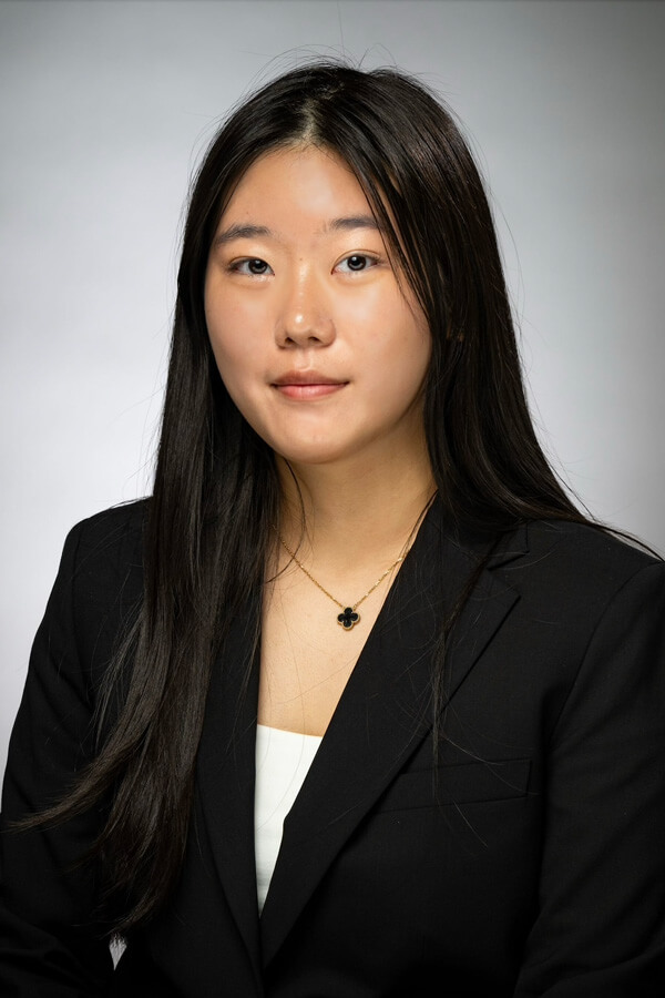 A headshot of Eliza Cho wearing a black blazer and a necklace.