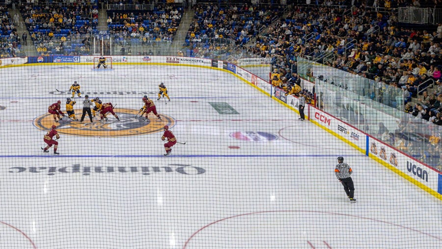 A wide shot of a hockey face off in front of a packed arena