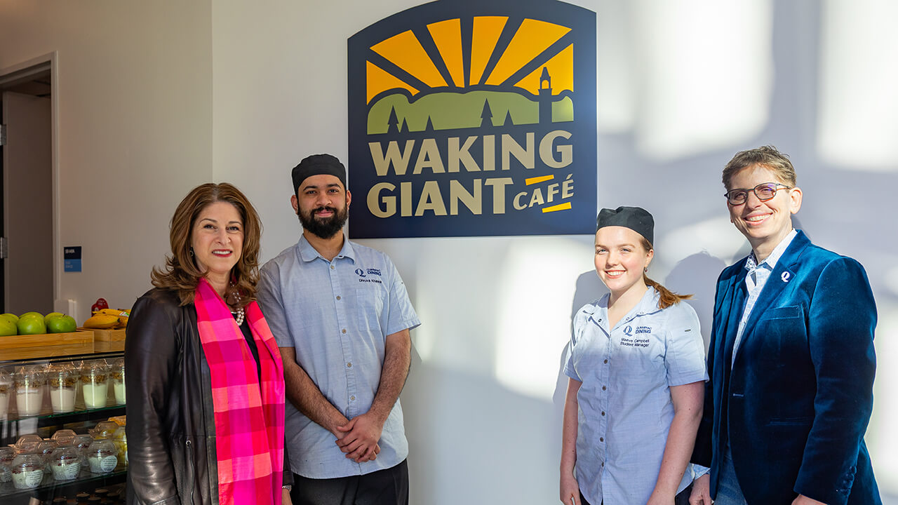 Provost, dean, and students in front of the Waking Giant Cafe sign
