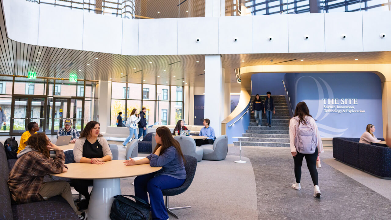 Quinnipiac community members utilizing the seating and walkway spaces in the lobby of the SITE building
