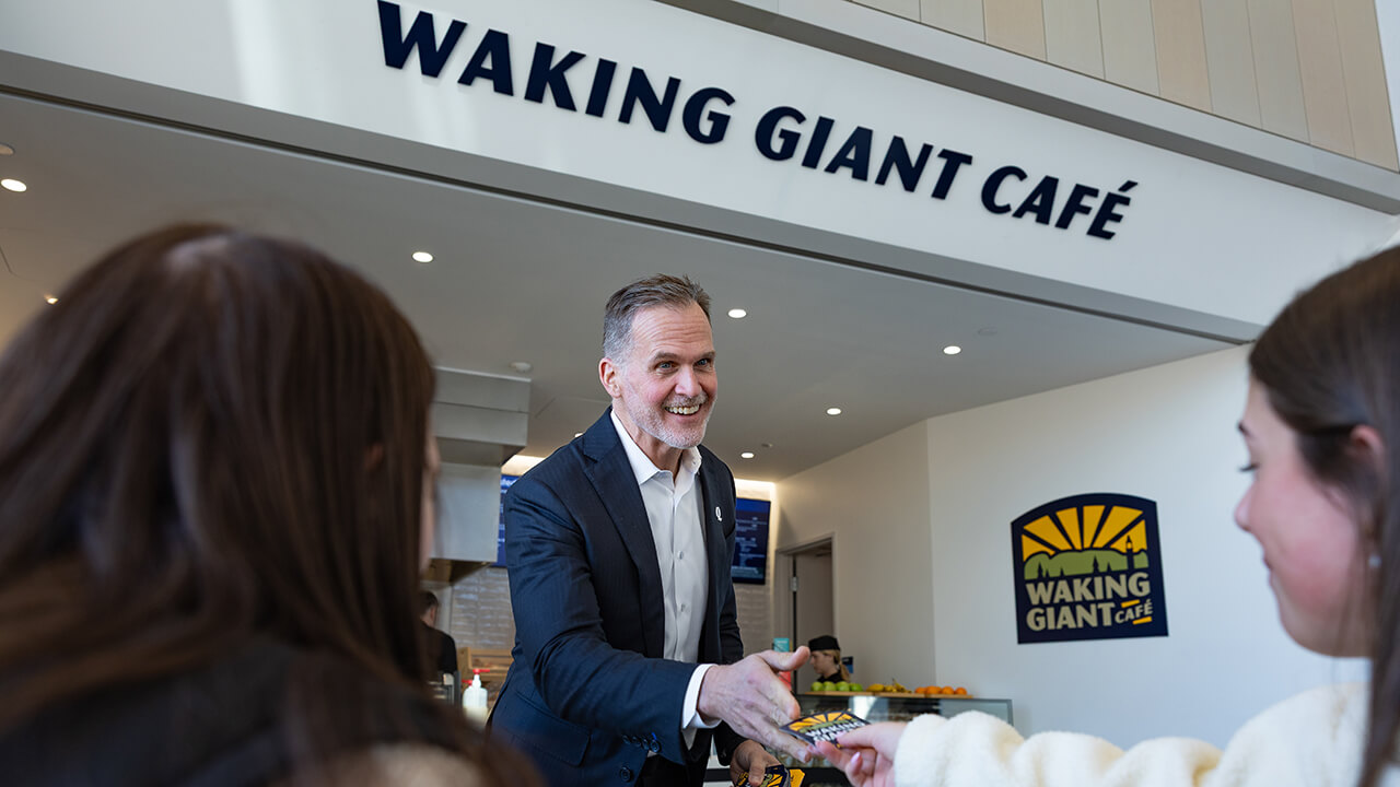 Staff and students smiling in front of the Waking Giant Cafe