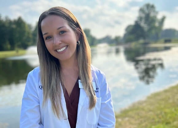 Claire Aurilio smiles for headshot in white coat.