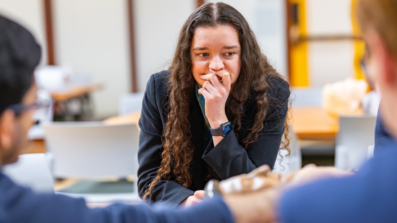 Student holds their hand to their chin with a focused look.