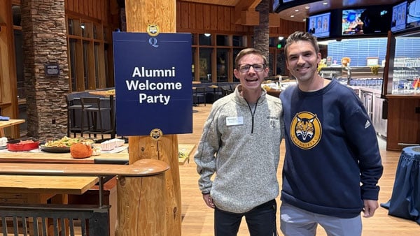 Kyle Adams and John Shepherd pose for a photo at On the Rocks for an alumni event