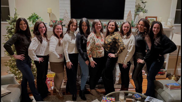 Quinnipiac alumna Kimberly Saccucci posing for a picture in a living room with several friends from Quinnipiac