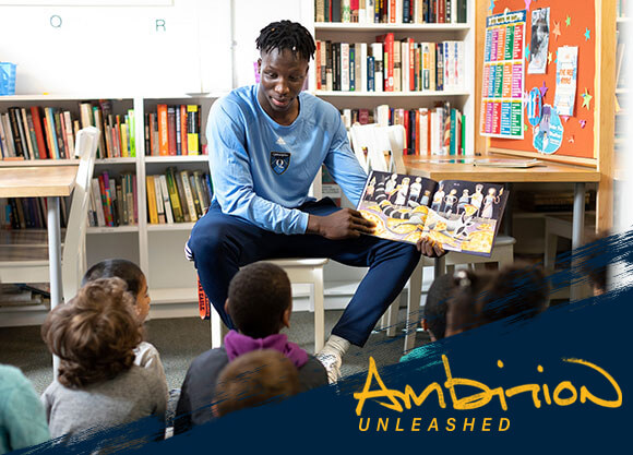 Ambition Unleashed: Abdulai Bundu reads a book to a class of children