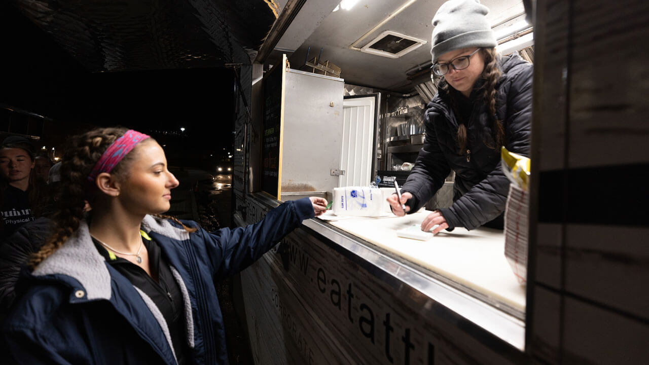 Girl order food at food truck for rec and wellness opening.