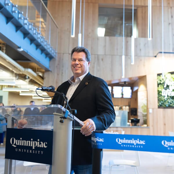 Robert Potter grins while standing at the podium in the Recreation and Wellness Center lobby