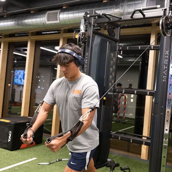 A student does an arm exercise using a weight machine