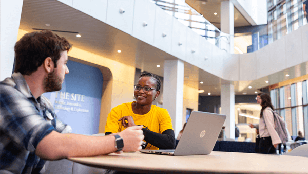 Two students talk together in the 3-story lobby of The SITE