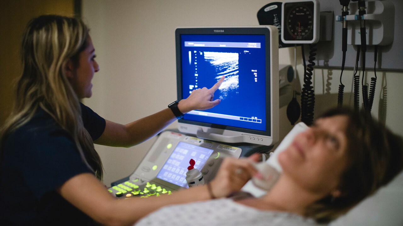 A medical student uses digital imaging equipment to examine a patient.