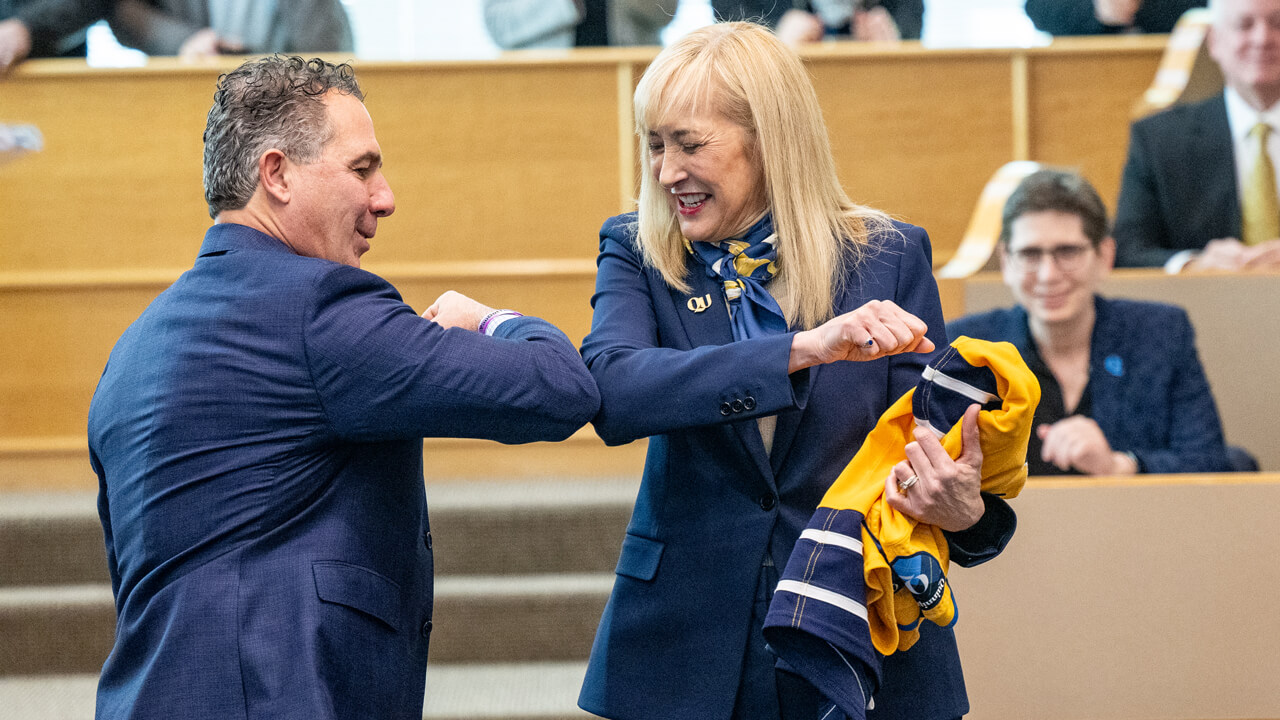 Marie Hardin and Chuck Saia laugh as they elbow bump