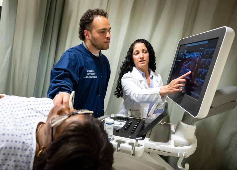 A student uses medical equipment with professional guidance.