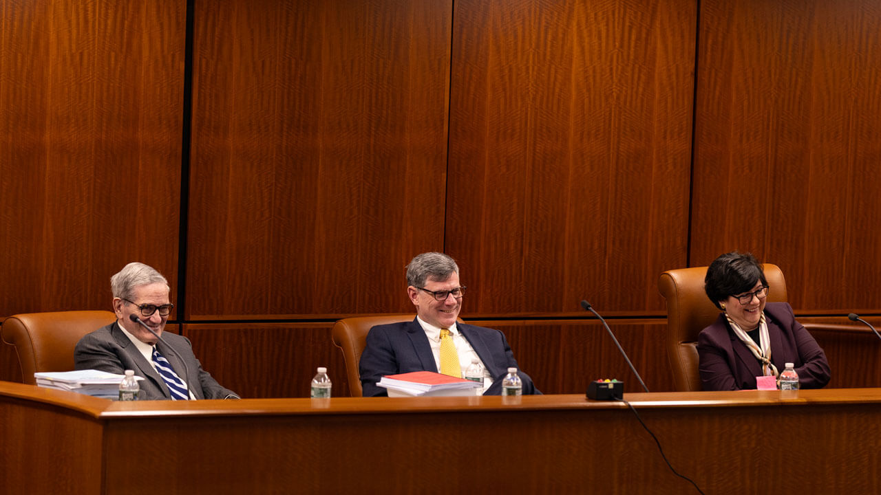 3 individuals looking at the front of the courtroom