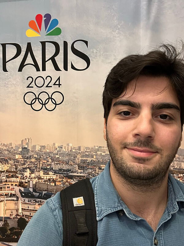 Quinnipiac Alumni posing in front of the Winter 2026 Olympics sign