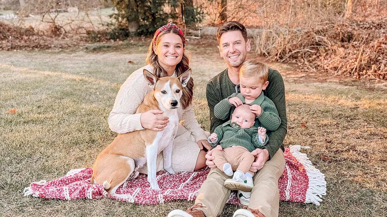 sarah and robin schuppert pose together with their two sons and dog