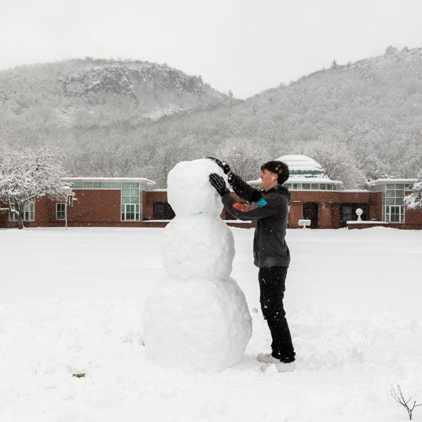 Student builds snowman on the Mount Carmel Campus quad.