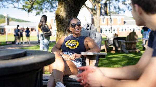 student sitting in adirondack chair on the quad