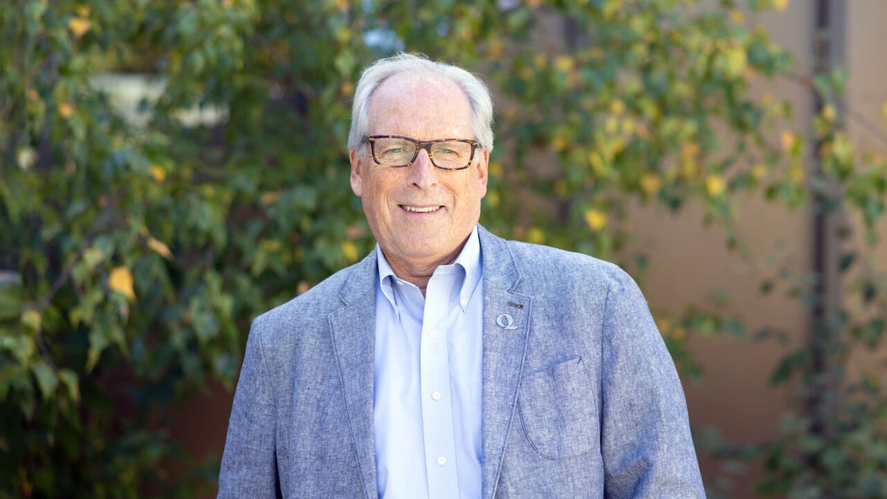 David Keiser smiling against a lush green tree.