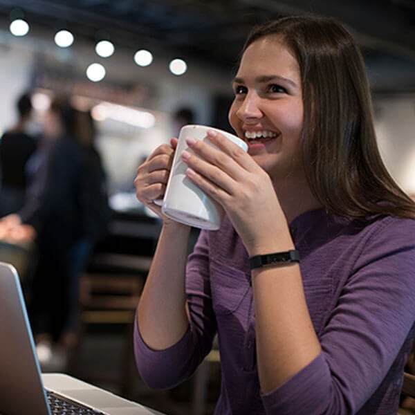 Student sips hot coffee out of a Starbucks mug on campus.