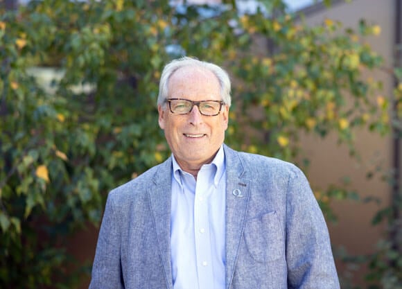 David Keiser smiling against a lush green tree