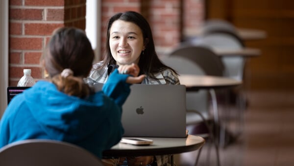 Students converse at a study table.