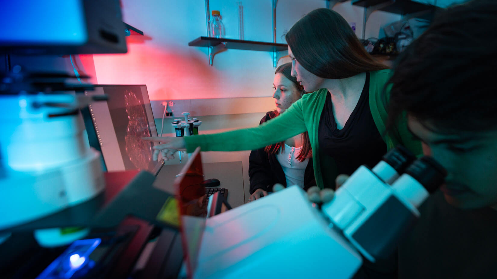 Students examine artifacts under a microscope.