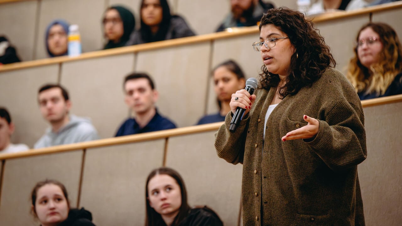 A student is standing and talking into a microphone in the audience.