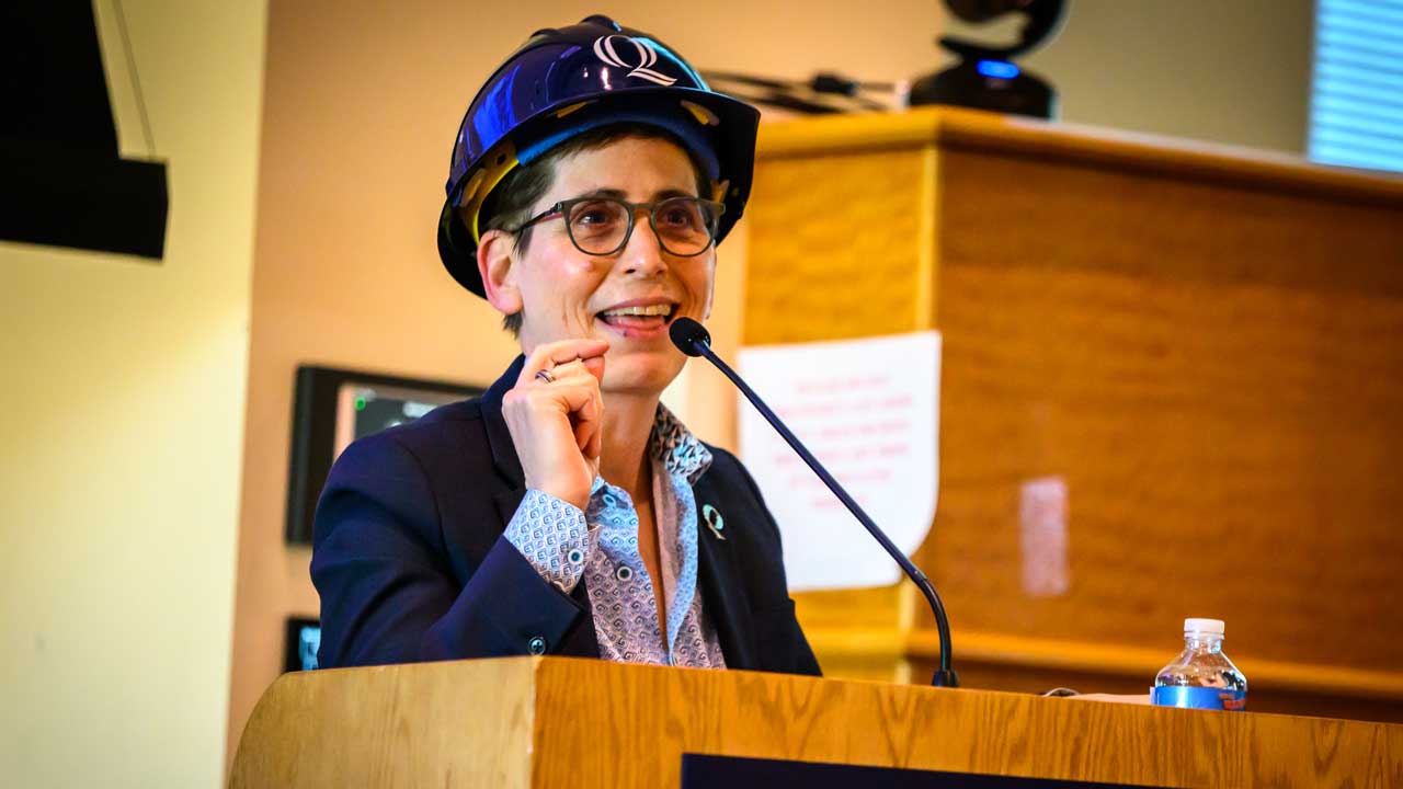 Provost Leibowitz speaking at a podium after receiving her hard hat