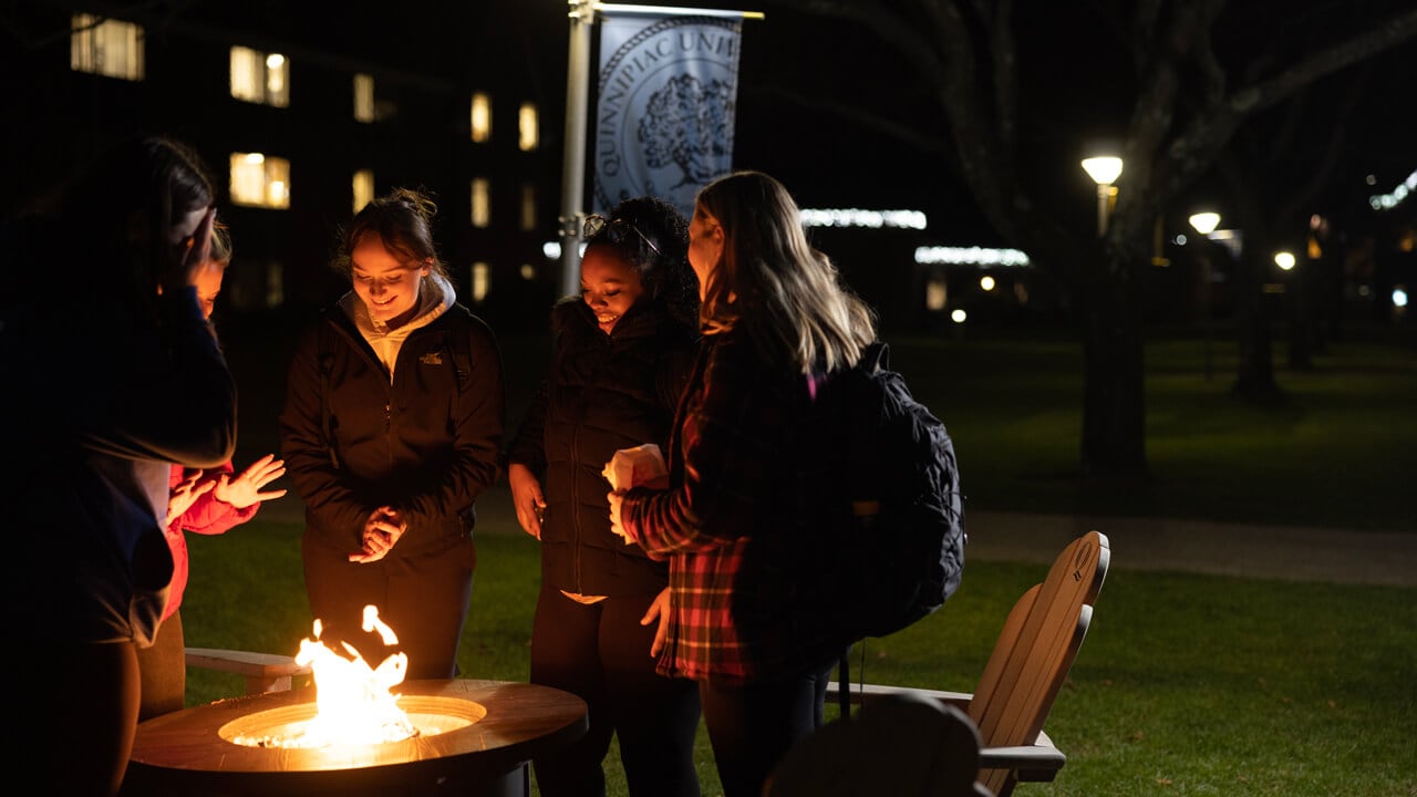 Students gather around a bonfire on main campus.