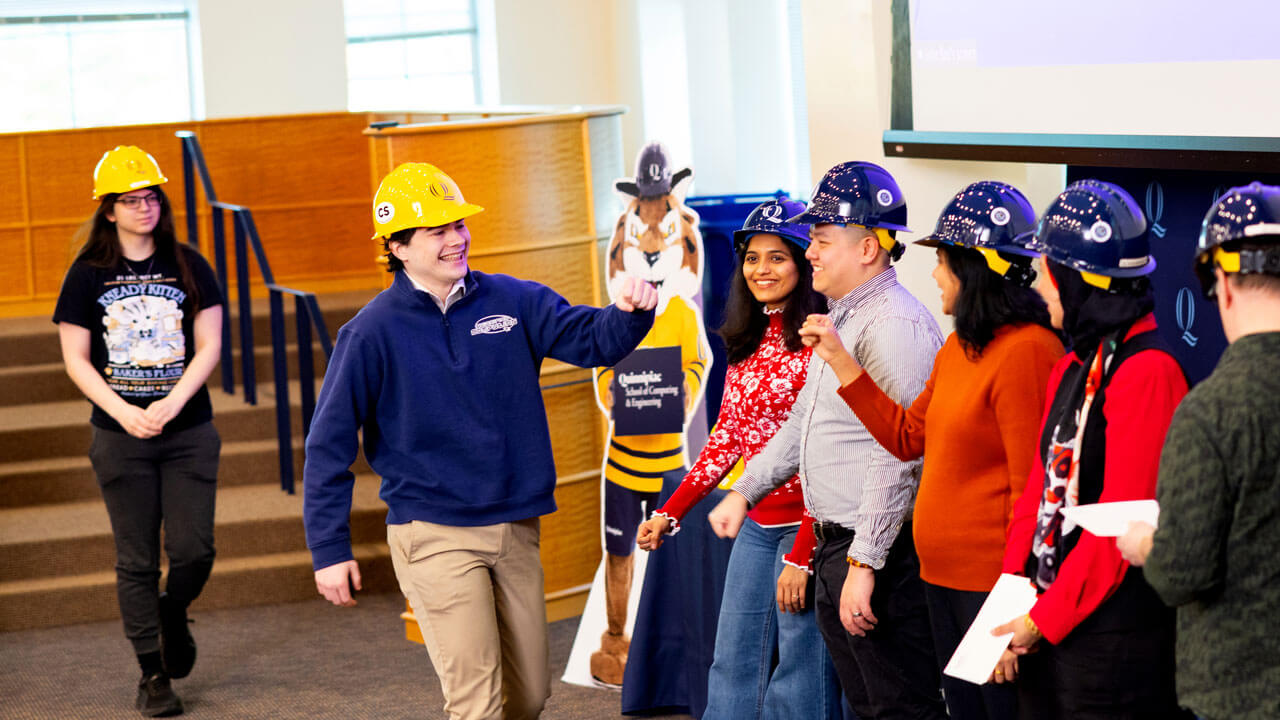 Student high fives friends while receiving hard hat
