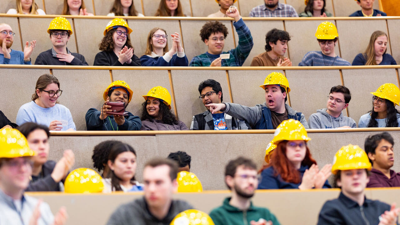 Students smile after receiving their hard hats