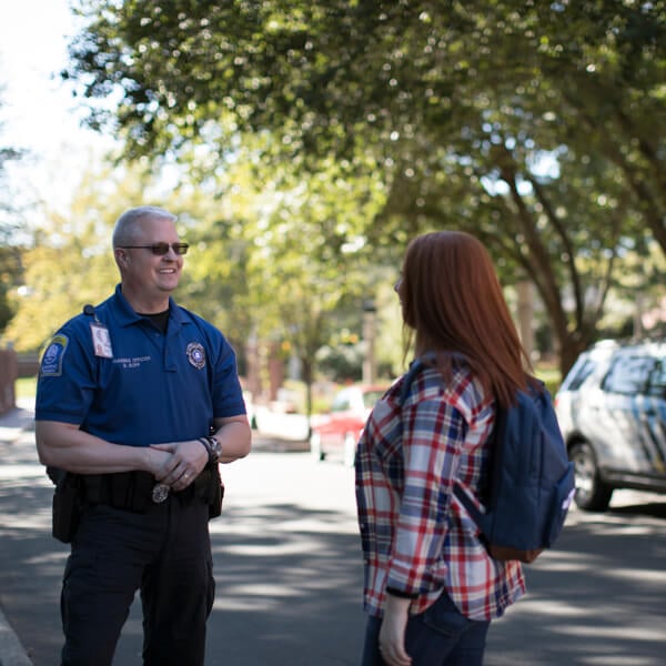 Public safety officer in uniform speaks with a student near a public safety vehicle