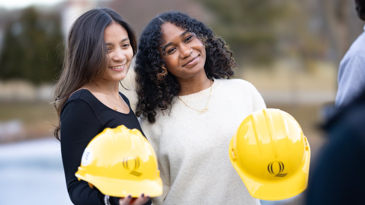 People pose for a photo holding their hard hats