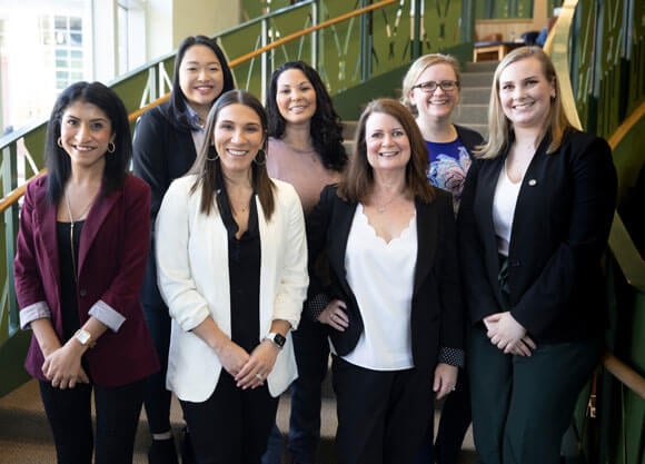 Group of women in tech standing in front of staircase in student center