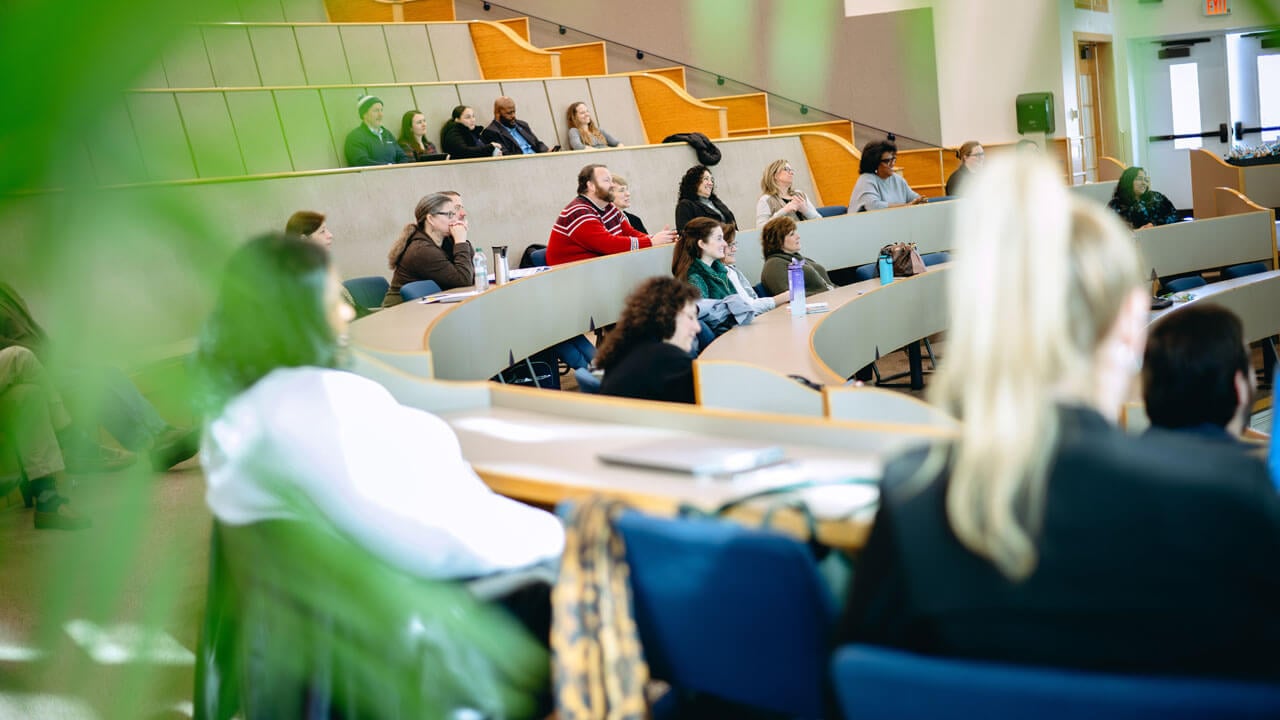 Wide shot of attendees sitting in the auditorium.