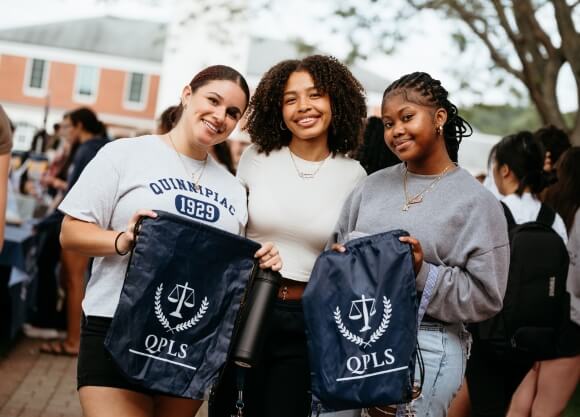 Students holding string bags for Quinnipiac's Pre-Law Society
