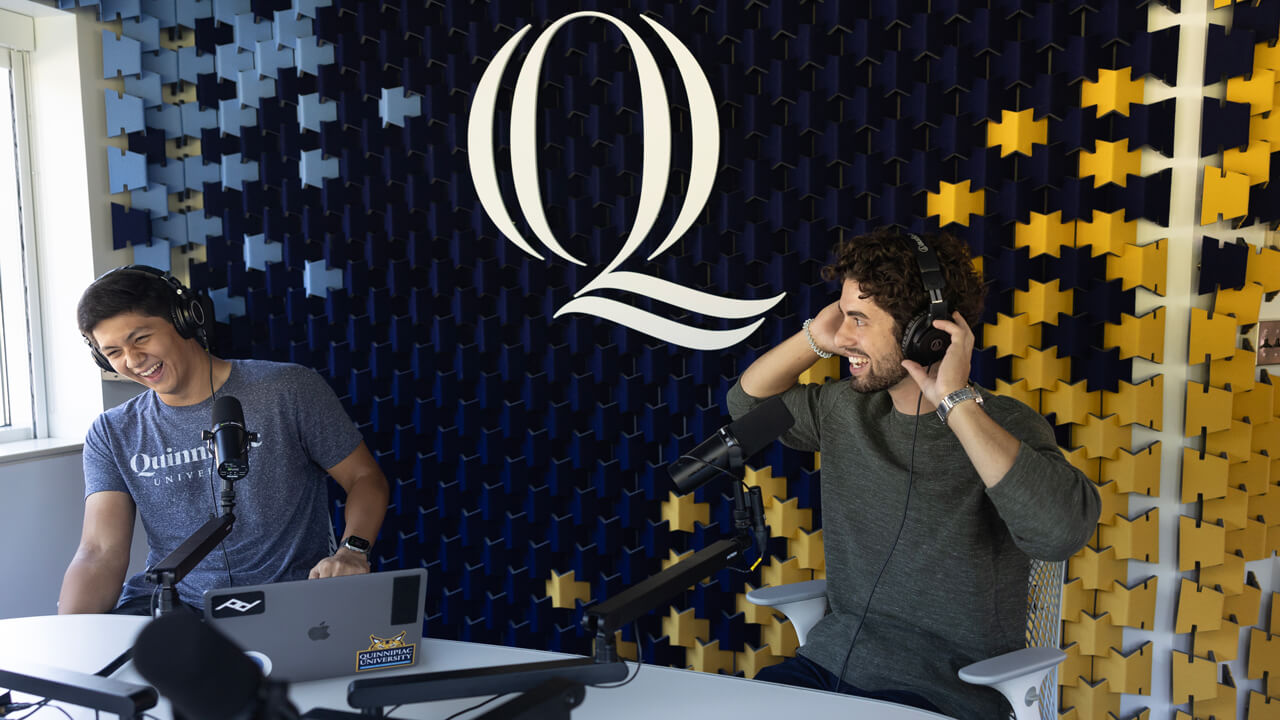 Quinnipiac students laughing while producing a podcast in a studio.