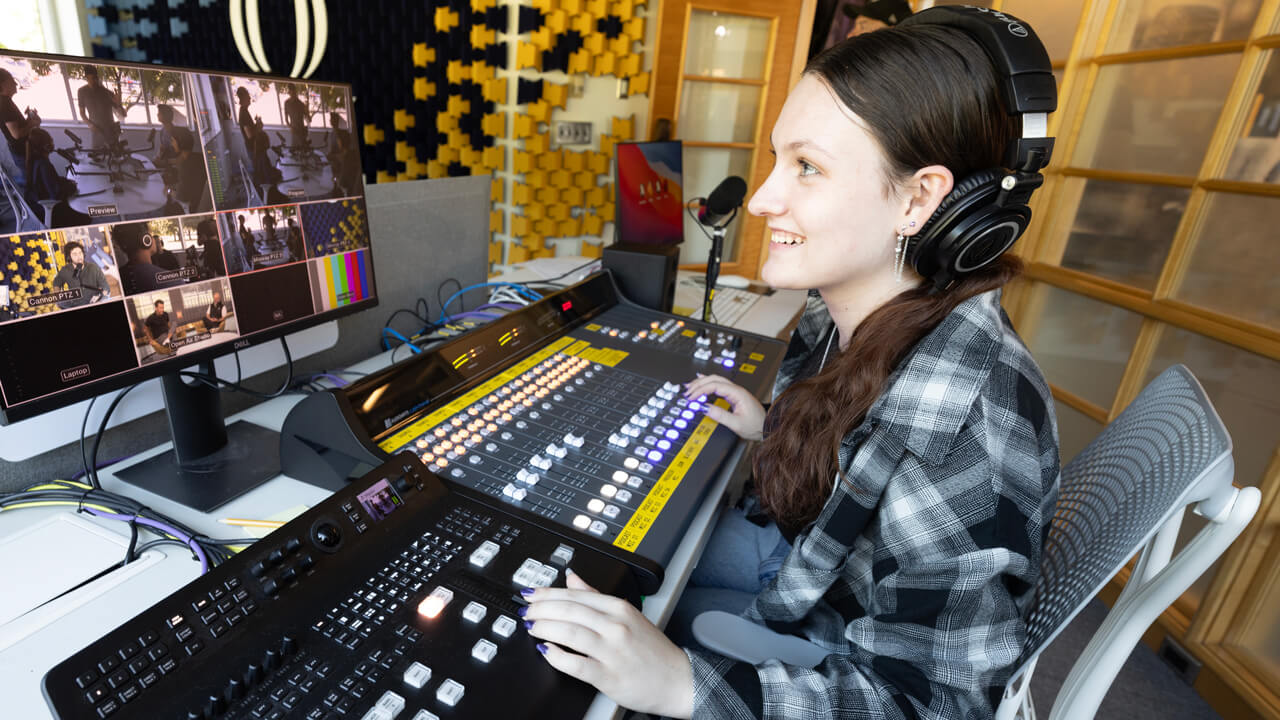 A student mixing audio channels in the Quinnipiac podcast studio.