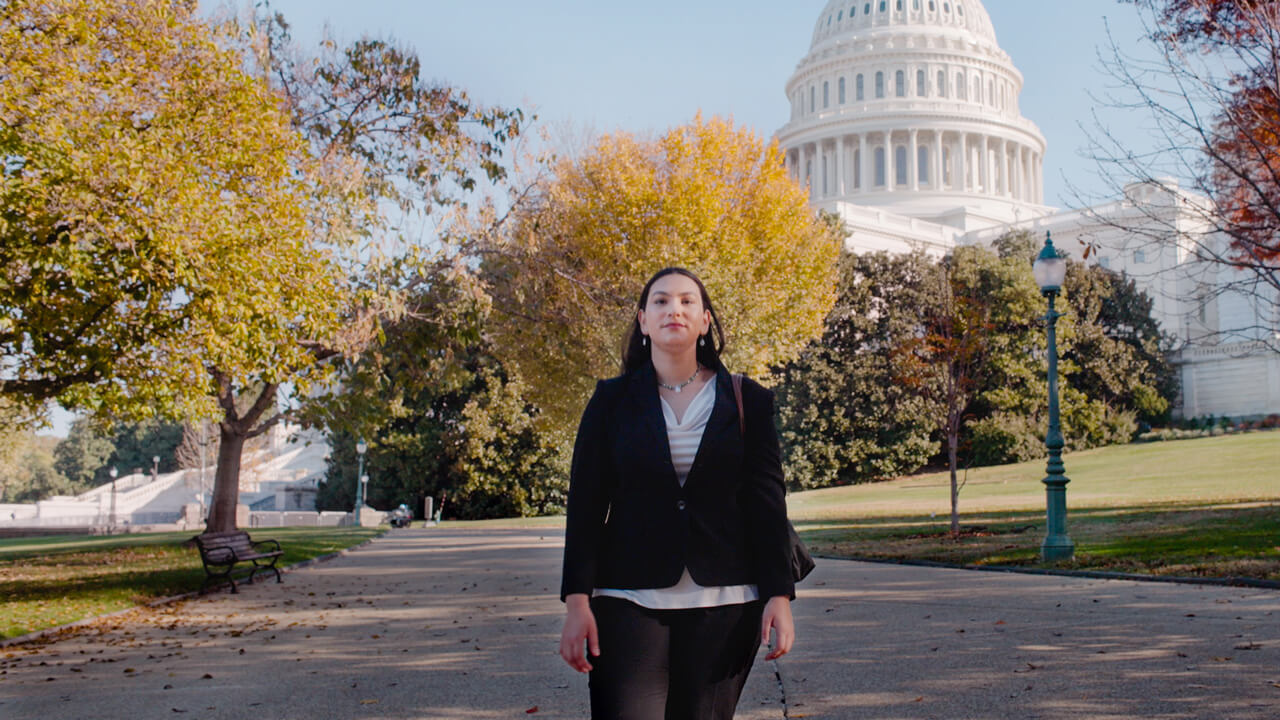 Ambar Pagan walks down the street in front of the Capitol building on a fall day