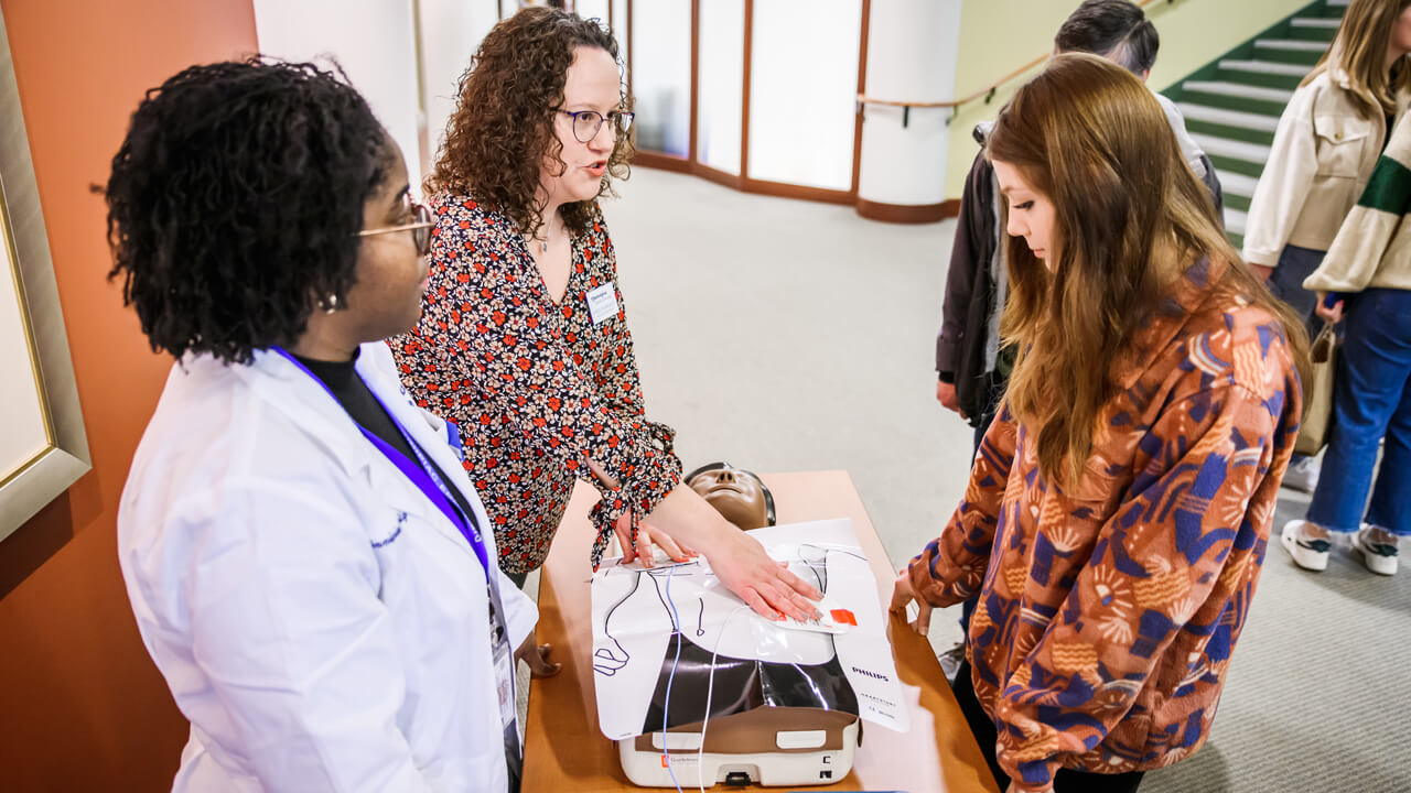 Student talks with a faculty member at an academic exploration day event.