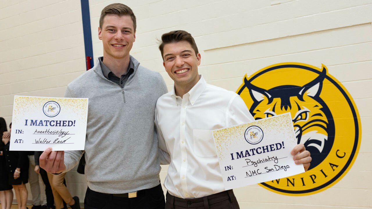 Medical students smile as they hold signs that they matched at Walter Reed and NMC San Diego.