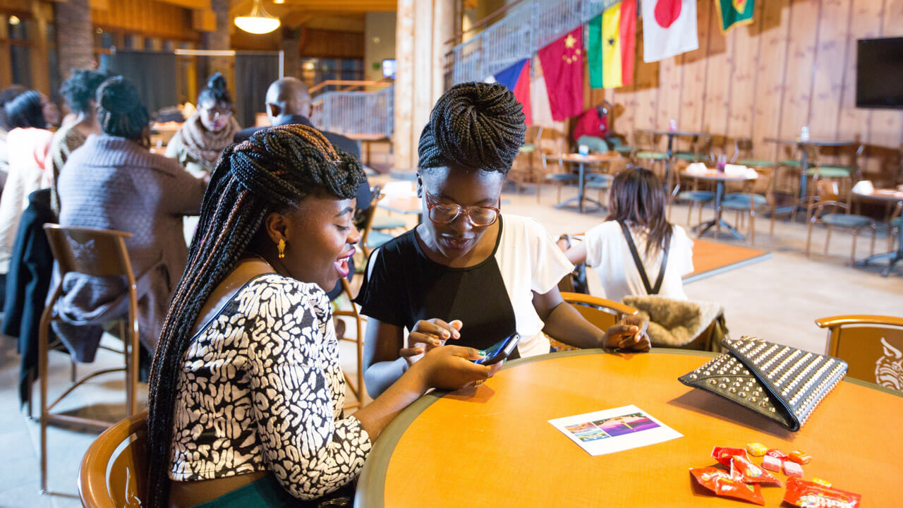 2 students of color sitting at a table laughing together