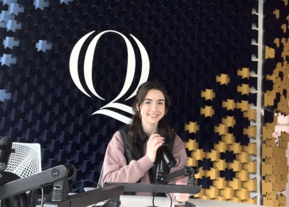 Photo of a student speaking into a microphone in the podcast studio.