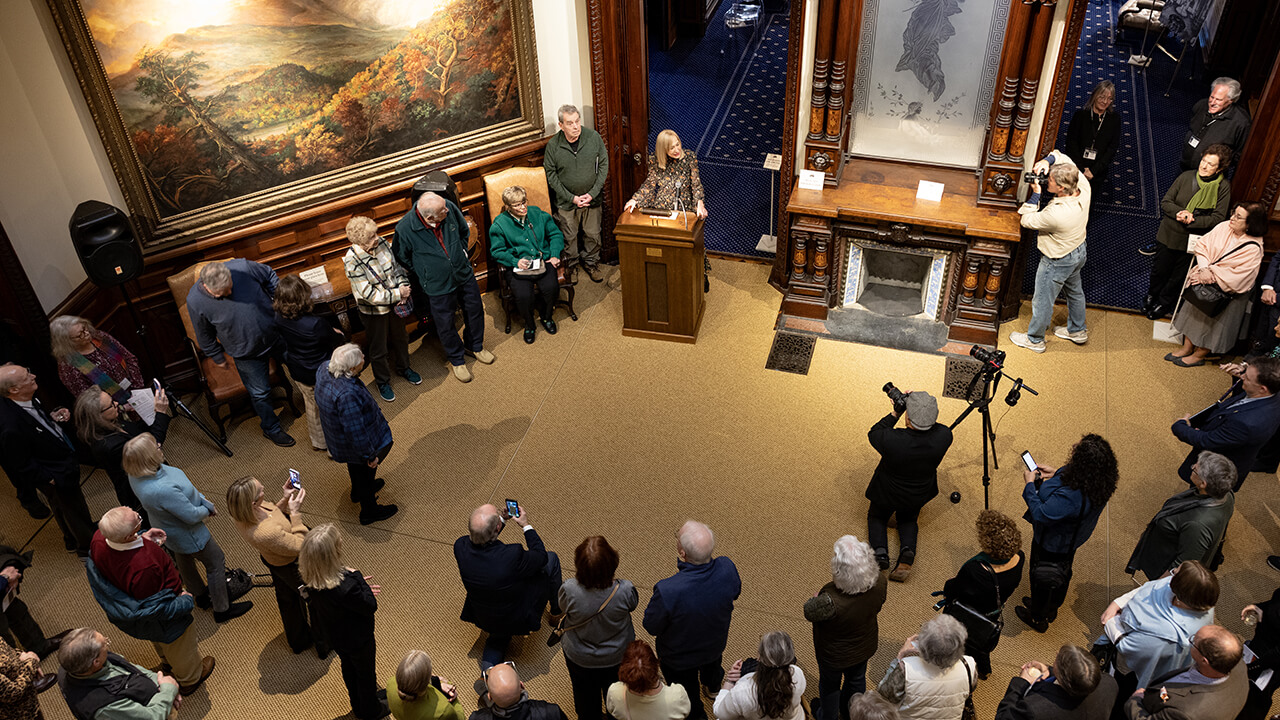 Group of community members gathering around President Marie Hardin speaking at the Ireland Great Hunger Museum