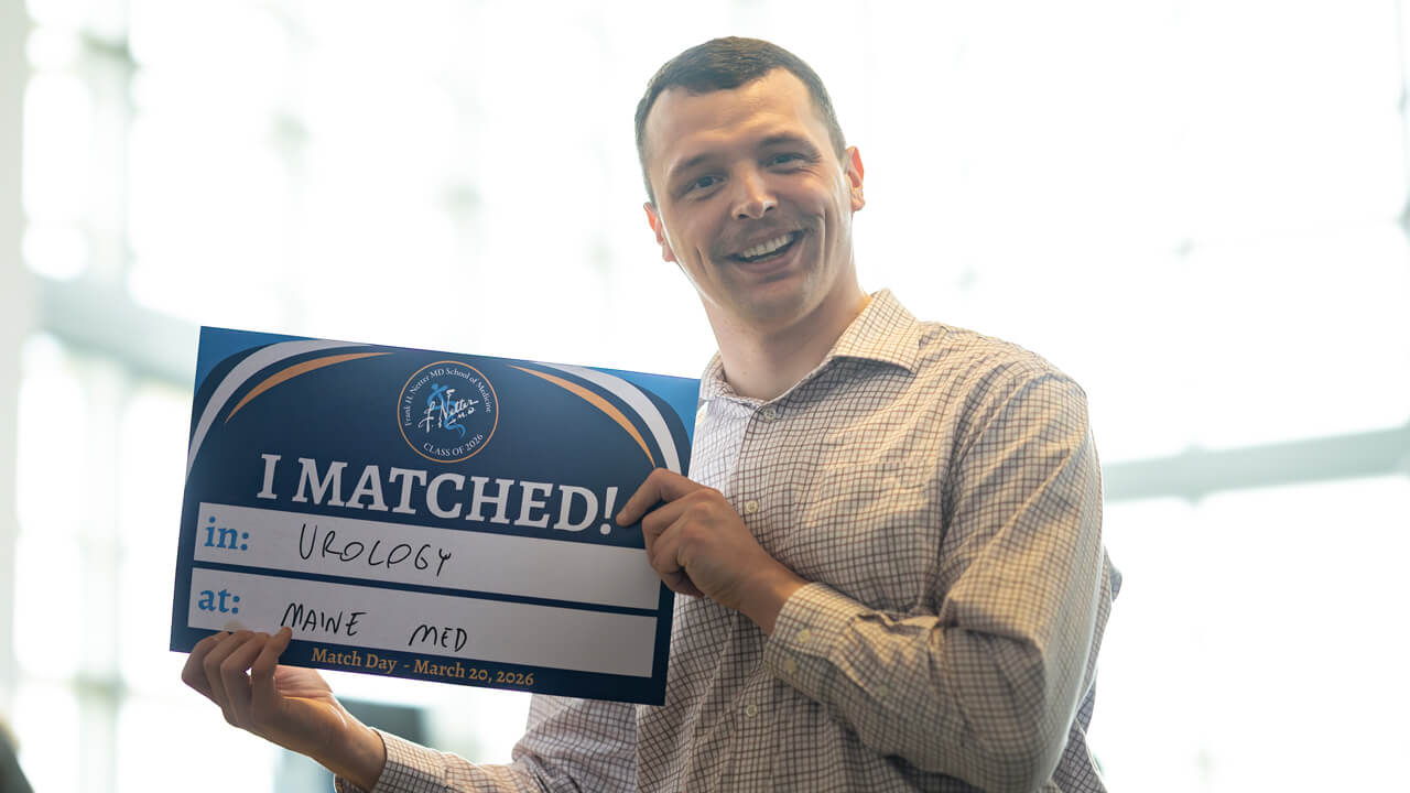 Andrew Kehm holds his "I matched in Urology at Maine Med" sign