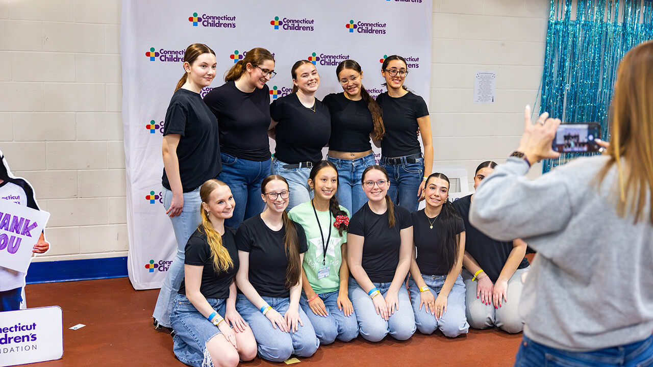 Students stand smiling and posing for a picture with QTHON Miracles