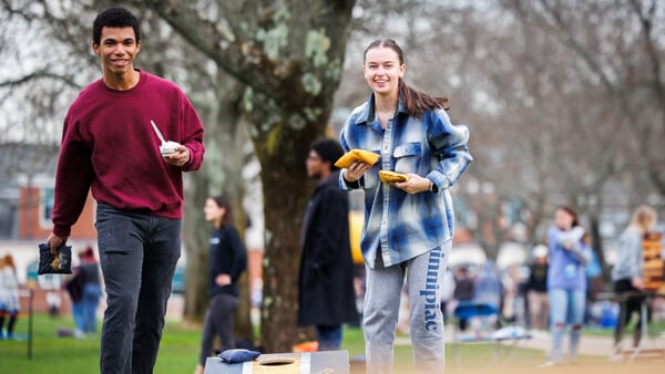 Two students play cornholl on the Quinnipiac quad